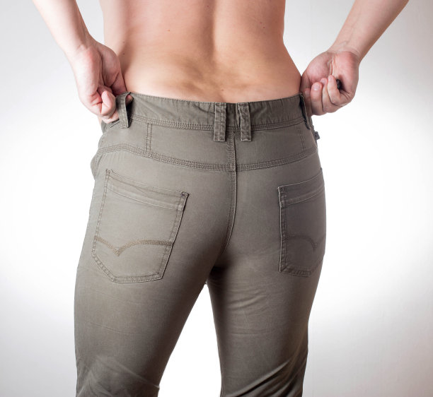 一名腹部有肥胖褶皱的超重男子穿着白色背景的绿色短裤。肥胖与营养不良的概念、饮食图片下载