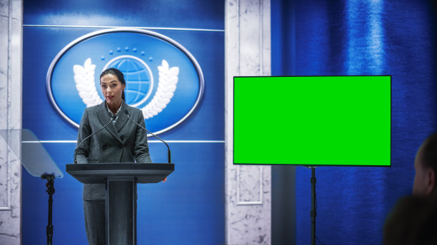 机构女代表在政府大楼举行的记者招待会上发言，并展示绿色屏风模型。新闻官员在峰会上的讲话。部长在国会。图片下载