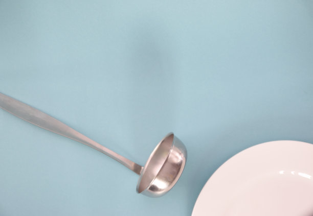 桌子上一个白盘子旁边放着一个长柄勺图片下载