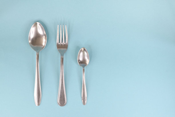 勺子、叉子和茶匙排成一列，放在一个浅色的背景上。图片下载