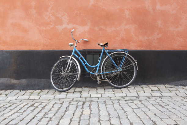 一辆老式自行车靠着一堵墙，在瑞典斯德哥尔摩的一条鹅卵石街道上。图片下载