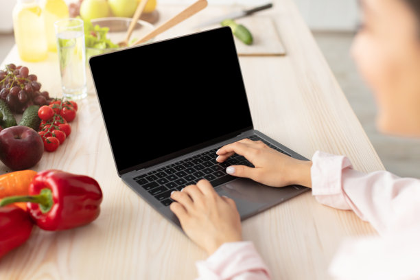 一个女人在厨房里用一个空屏幕的电脑做模型图片下载