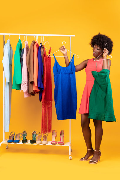非洲女人在两件衣服之间选择，黄色背景图片下载
