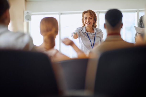 女讲师微笑着指着其中一名学生与学生交流图片下载