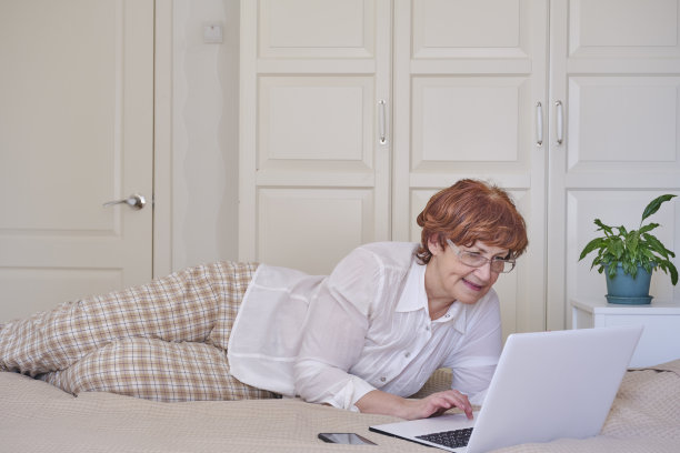 在家里使用笔记本电脑的资深女性。快乐的退休人士网上购物。图片下载
