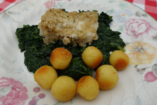 用面包屑烹制的波洛克鳕鱼，配以煮熟的菠菜和炸土豆，做成球状图片下载