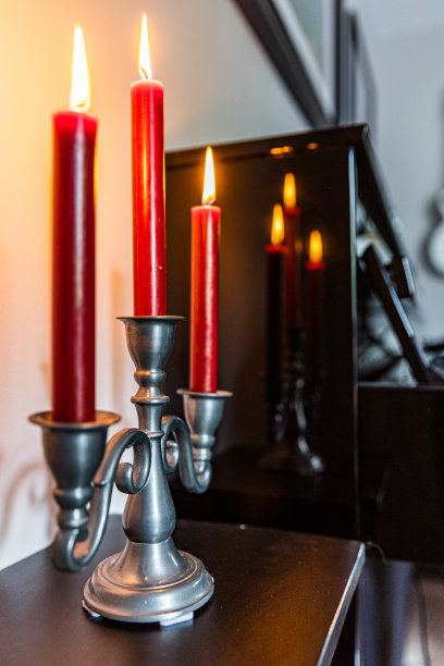 古董烛台上有三支燃烧的红色蜡烛，前面是一架黑色立式钢琴图片下载