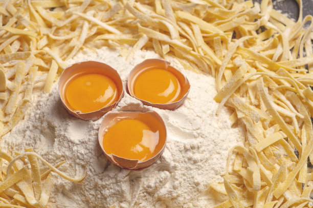 新鲜面食背景。家庭厨房自制的意大利面，用新鲜的鸡蛋和面粉在木背景上做。意大利食物和烹饪的概念图片下载