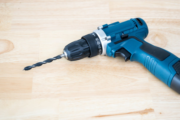蓝色的无绳电钻放在一张木桌上图片下载