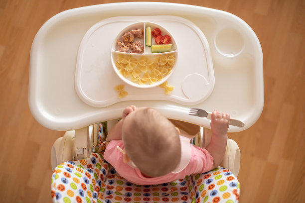 一岁女孩在婴儿餐椅上均衡饮食，为孩子提供健康均衡的营养图片下载