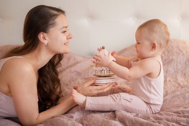 年轻美丽的母亲和她的小女儿在卧室里玩手工制作的木制玩具图片下载