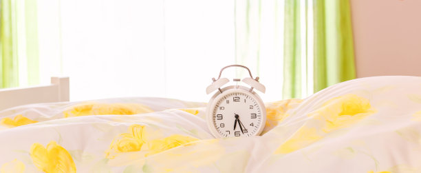 床上的钟。闹钟放在羽绒被上，枕头上。广告的概念图片下载