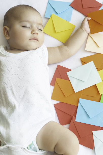 婴儿拿着橙色的信封图片下载