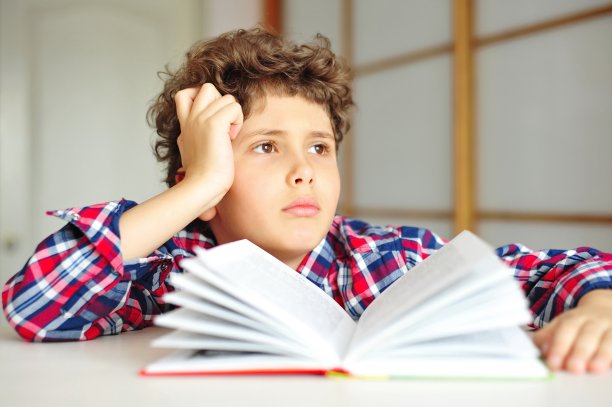 小男孩卷着头发做作业，看起来若有所思，若有所思图片下载