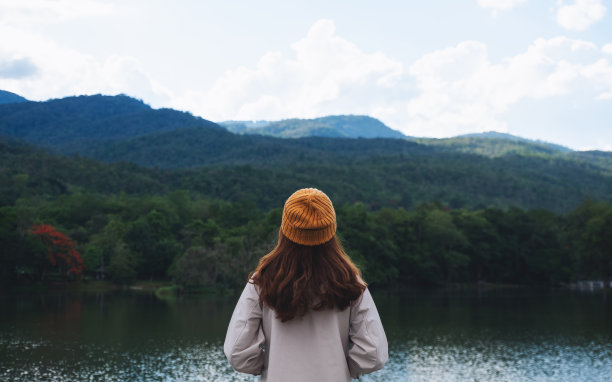 一个女人看着湖边美丽的绿色山脉图片下载