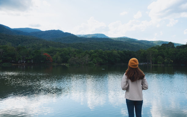 一个女人看着湖边美丽的绿色山脉图片下载
