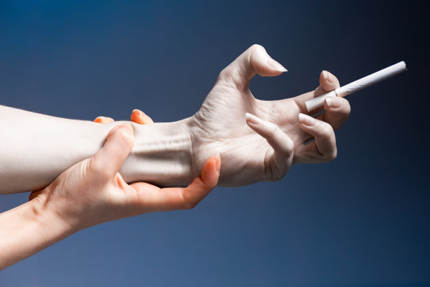 尼古丁上瘾。痛苦，扭曲着女性的双手，特写，握着一根香烟。试图戒烟。深蓝色的背景。世界无烟日的概念图片下载