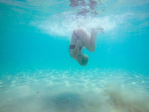 水下照片，一个女人在比基尼潜水在绿松石海水。图片下载