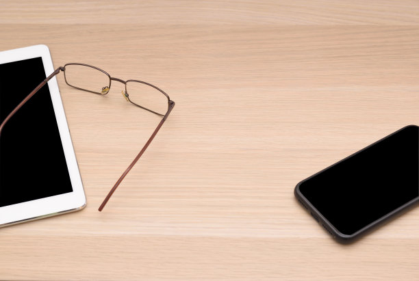 把眼镜、平板电脑和智能手机放在木头桌面上。图片下载