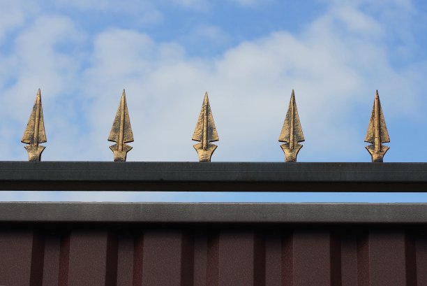 黑褐色的墙上挂着一排黄色锋利的铁棒图片下载