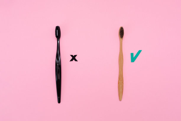 环保产品。粉色背景的塑料和竹子牙刷。平的。选择卫生用品的概念图片下载