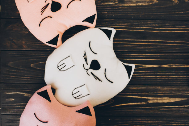 木制背景上的可爱的猫形枕头，俯视图。粉色和白色的猫形坐垫图片下载