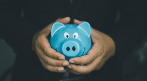穿西装的男人手里拿着蓝色的存钱罐。储蓄和金融投资的概念图片下载