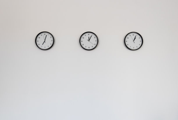 三个经典的时钟孤立地挂在浅灰色的墙壁背景上。图片下载