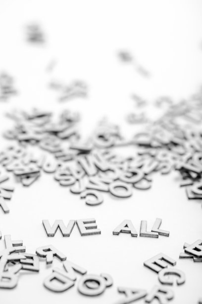 短语“我们所有人”是由小木头字母和随机字母堆在白色背景上。一个抽象的想法，将被证明在激励的话。黑与白的照片。图片下载