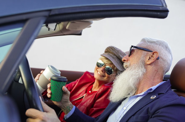 一对夫妇在一辆敞篷车里喝咖啡。退休的人们欢度一个美妙的假期。公路旅行，假期，夫妇和人的概念。——形象。图片下载