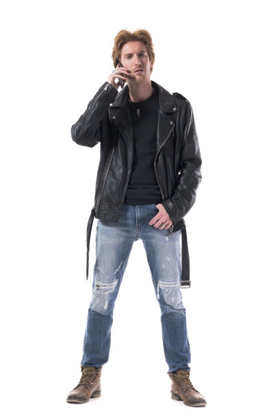 持怀疑态度的年轻摇滚型男穿着皮夹克在打手机。图片下载
