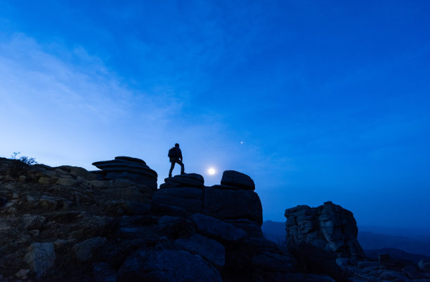 月光下，户外徒步者在山上爬山的剪影图片下载