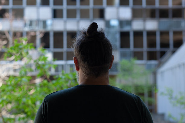 一名男子站在被毁的废弃建筑前，背对着摄像机图片下载