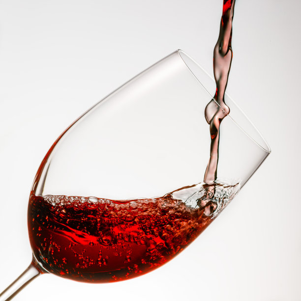红酒倒进白色背景的玻璃杯中图片下载