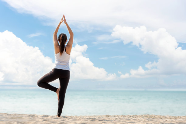 生活方式运动女性瑜伽锻炼和姿势健康的生活。年轻女孩或人们摆平衡身体，重要的禅和冥想锻炼和健身运动户外沙滩。大海和蓝天的背景。卫生保健的概念图片下载