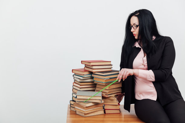 美丽的女老师在课堂上与一堆教育书籍的桌子图片下载