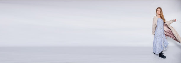 美丽的女孩在米色雨衣摆姿势在工作室在灰色的背景图片下载