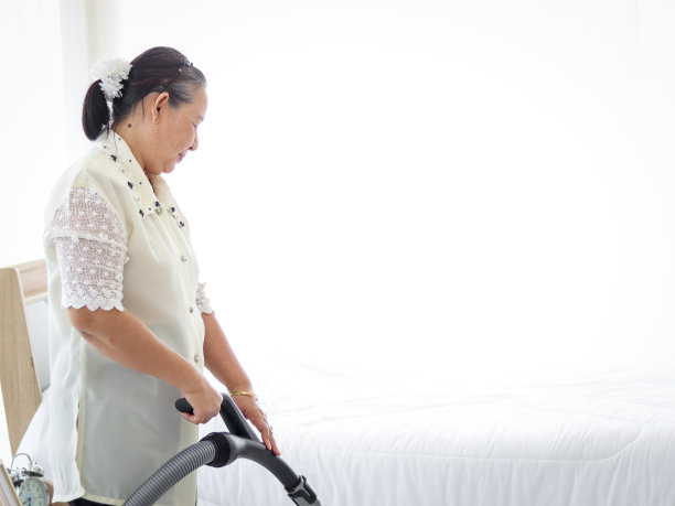 快乐微笑的亚洲老年妇女家庭主妇在卧室用吸尘器吸尘，奶奶在家里做家务。图片下载