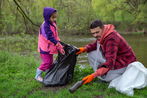 爸爸和女儿，用垃圾袋，清洁环境的垃圾。图片下载