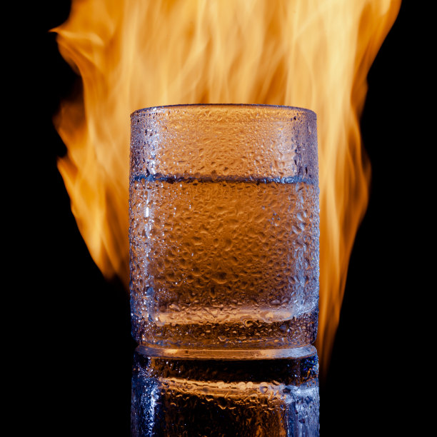 在黑色背景下，一杯冒汗的水着火了图片下载