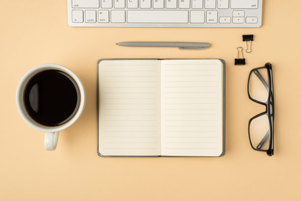 俯视图照片的工作场所组成杯，咖啡杯打开灰色日记，白色键盘，钢笔和活页夹上孤立的米色背景与copyspace图片下载