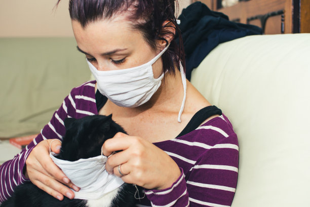 戴着保护面罩的女人拿着一张猫的照片图片下载