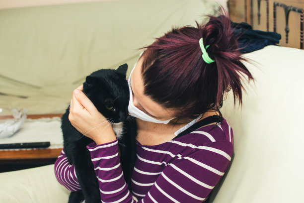 戴着保护面罩的女人拿着一张猫的照片图片下载