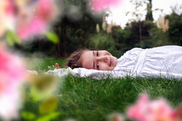 快乐的小女孩躺在绿草地上图片下载