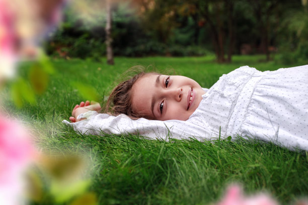 快乐的小女孩躺在绿草地上图片下载