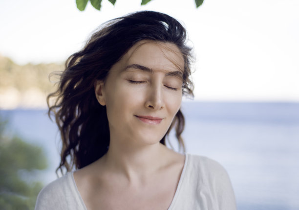 一位平静的年轻女子享受着新鲜的海上空气图片下载
