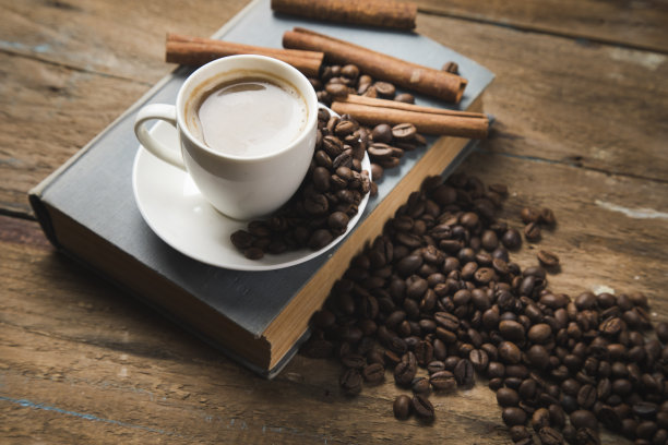木桌上放着一杯咖啡、咖啡籽、肉桂和一本书图片下载