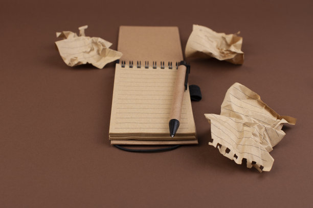 皱巴巴的纸团和一个笔记本，还有一个用来做笔记的手图片下载