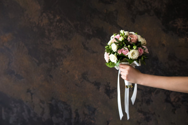 黑色背景下，女性手握婚礼花束图片下载