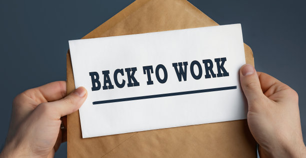 一个男性的手握着手工信封的特写，上面写着“回到工作上，蓝色背景”图片下载